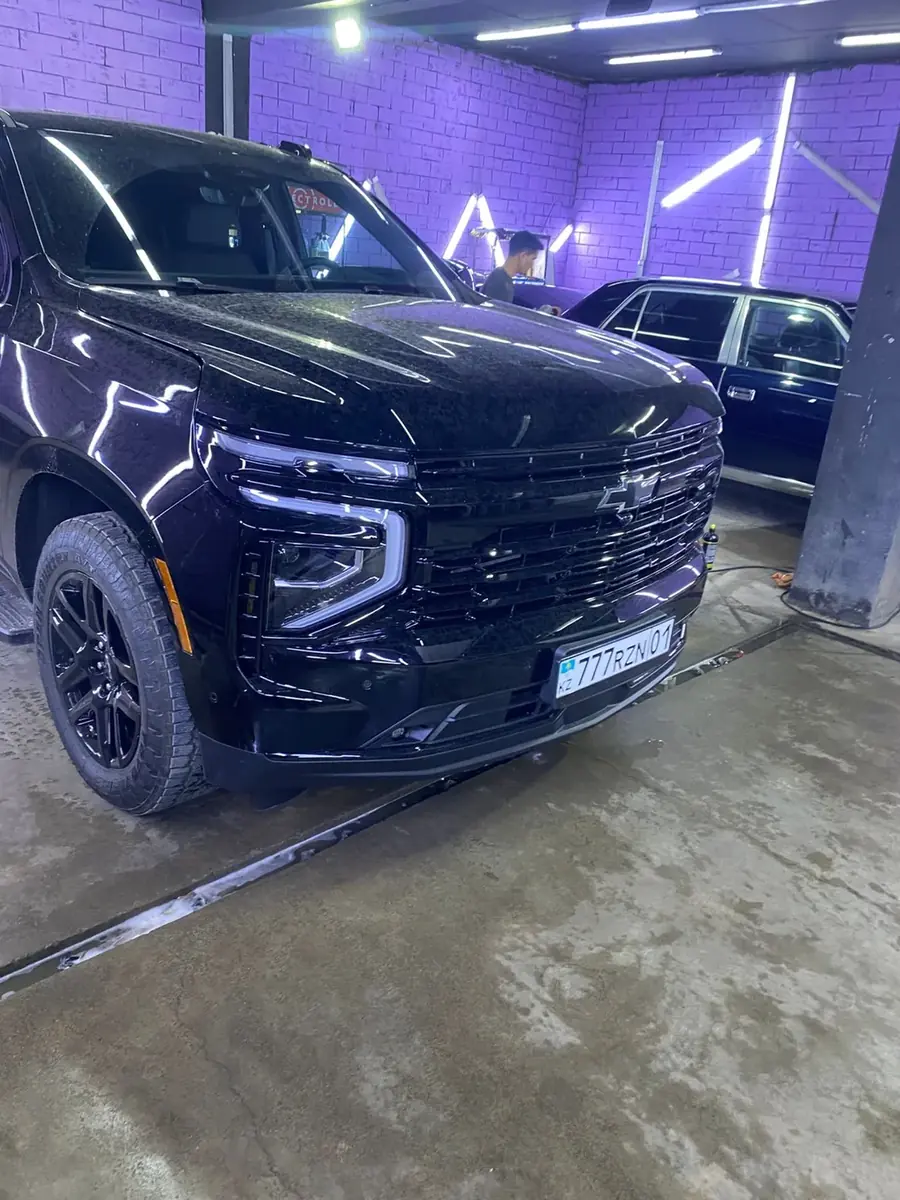 Чёрный Chevrolet Tahoe в фиолетовом неоне цеха